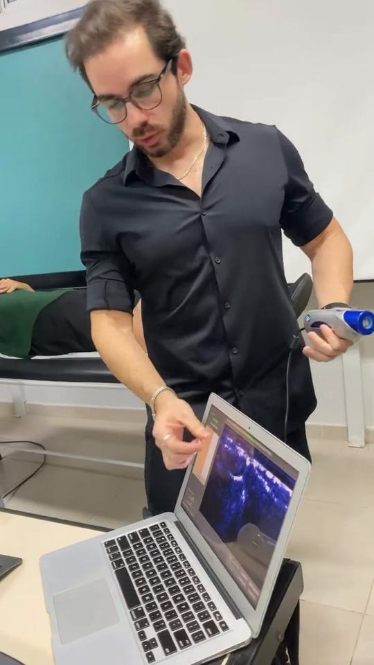 Thiago Benevides durante uma avaliação, com o aparelho na mão e o notebook ao lado